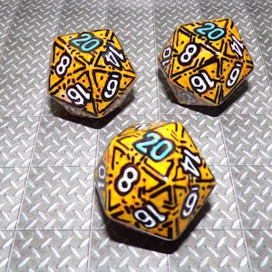 May include: Three yellow 20-sided dice with black and white markings and blue numbers. The dice have a textured, speckled surface.