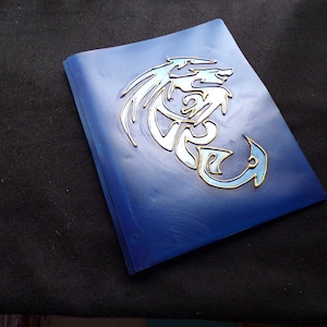 May include: A blue plastic binder with a silver and gold dragon design.