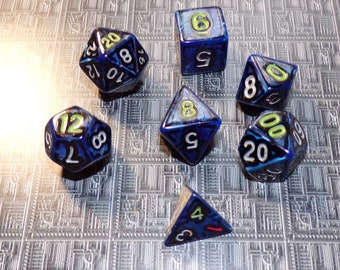 May include: A set of six blue and black dice with yellow numbers. The dice are on a gray and white patterned surface.