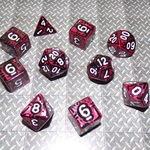 May include: A collection of multi-sided dice for tabletop gaming. The dice are various shapes, including a triangle, cube, and a 20-sided die. Each die is a translucent red with white numbers and black outlines.