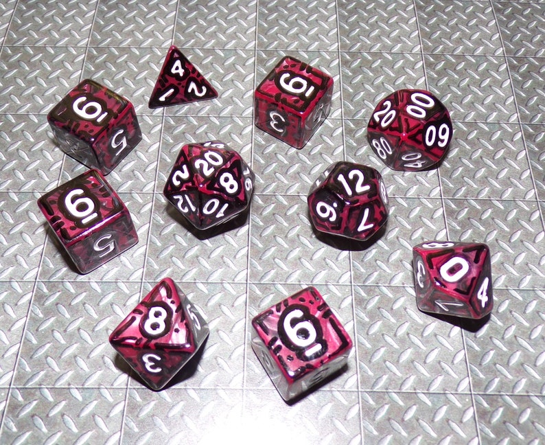 May include: A collection of multi-sided dice for tabletop gaming. The dice are various shapes, including a triangle, cube, and a 20-sided die. Each die is a translucent red with white numbers and black outlines.