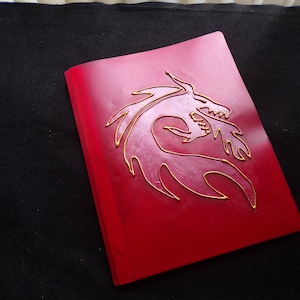 May include: A red folder with a gold dragon design embossed on the front.