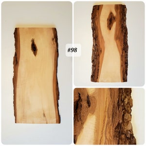 Puede incluir: Una losa de madera marr&oacute;n claro con un borde de corteza natural. La madera tiene un nudo en el centro y un patr&oacute;n de veta marr&oacute;n claro. La losa es #98.