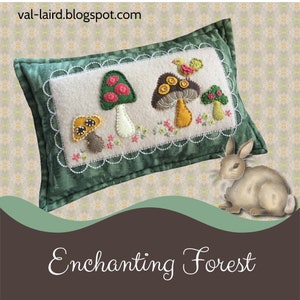 May include: A green and white pillow with an embroidered design of mushrooms and a bird. The pillow is on a patterned background with a small brown rabbit in the foreground. The text "Enchanting Forest" is at the bottom of the image.