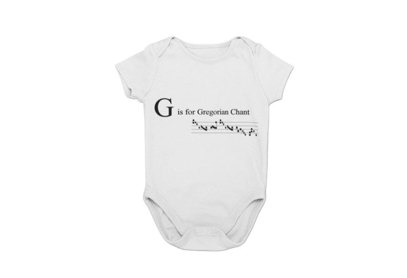 May include: White baby bodysuit with the text "G is for Gregorian Chant" in black. Below the text is a musical staff with notes. The bodysuit is a one-piece garment with short sleeves.