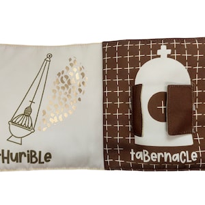 以下が含まれることがあります： 2 ページ開きの布製本。片方のページには、単語「tHuriBlE」が付いた金色の香炉のイラストが描かれています。もう一方のページには、単語「taBERNACLE」が付いた幕屋のイラストが描かれています。背景は白十字の茶色です。