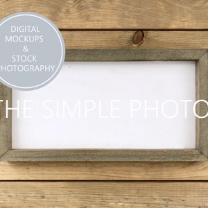 Pode incluir: Uma moldura de madeira rústica com fundo branco. A moldura está sobre uma superfície de madeira. O texto "THE SIMPLE PHOTO" está impresso em branco na moldura.