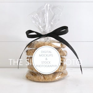 May include: A clear plastic bag filled with a stack of oatmeal cookies tied with a black ribbon. A white circle sticker with the text "DIGITAL MOCKUPS & STOCK PHOTOGRAPHY" is attached to the bag.