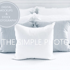 Op de afbeelding: Een verzameling witte en gestreepte kussens op een bed. De kussens hebben verschillende vormen en maten, sommige met een klassiek blauw-wit streepjespatroon. De afbeelding bevat de tekst "DIGITAL MOCKUPS & STOCK PHOTOGRAPHY" en "THE SIMPLE PHOTO".