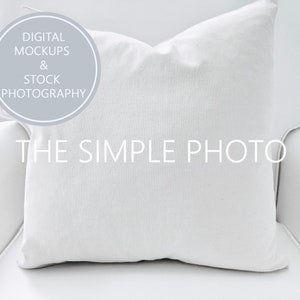 May include: White pillow on a white chair. The pillow is made of a soft, textured fabric. The text "THE SIMPLE PHOTO" is printed on the pillow.