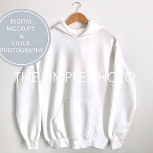 May include: White hooded sweatshirt with a pouch pocket. The sweatshirt is hanging on a hanger against a white background.