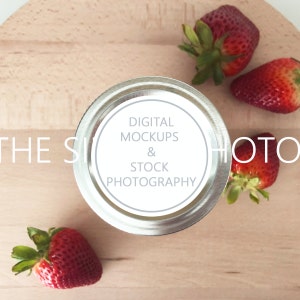 May include: A silver jar lid with a white label that reads "DIGITAL MOCKUPS & STOCK PHOTOGRAPHY" on a wooden surface with red strawberries.