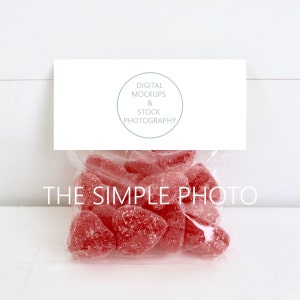May include: A clear plastic bag filled with red heart-shaped sweets. The bag has a white card attached to it with the text "DIGITAL MOCKUPS & STOCK PHOTOGRAPHY" and a circle with the text "THE SIMPLE PHOTO".