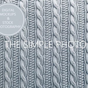 May include: A close-up of a light gray knitted fabric with a cable knit pattern. The fabric has a soft, textured surface.