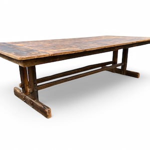 May include: A rustic, rectangular wooden table with a distressed finish. The table has a dark brown top and a sturdy base with angled legs. The table is approximately 96 inches long.