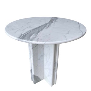 May include: A round marble table with a white and gray veined pattern. The table has a circular top and a pedestal base. The table is approximately 30 inches in diameter and 28 inches tall.