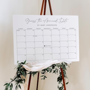 Peut inclure: Un calendrier blanc avec une grille noire et le texte "Devinez la date d'arrivée de bébé Anderson". Le calendrier est configuré du 22 avril au 28 mai. Un cœur est placé le 15 mai, intitulé "Date d'échéance".