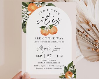 Puede incluir: Una invitación a un baby shower con el texto "Two Little Cuties Are On The Way". El diseño incluye ilustraciones de naranjas y detalles florales. La invitación también incluye los detalles del evento y la información de RSVP.