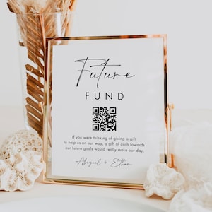 May include: A gold-framed sign with the words "Future Fund" in black script. Below is a QR code and text that reads, "If you were thinking of giving a gift to help us on our way..." The sign is a wedding or event accessory.