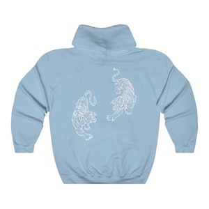 May include: A light blue hoodie featuring a white graphic of two tigers facing each other.