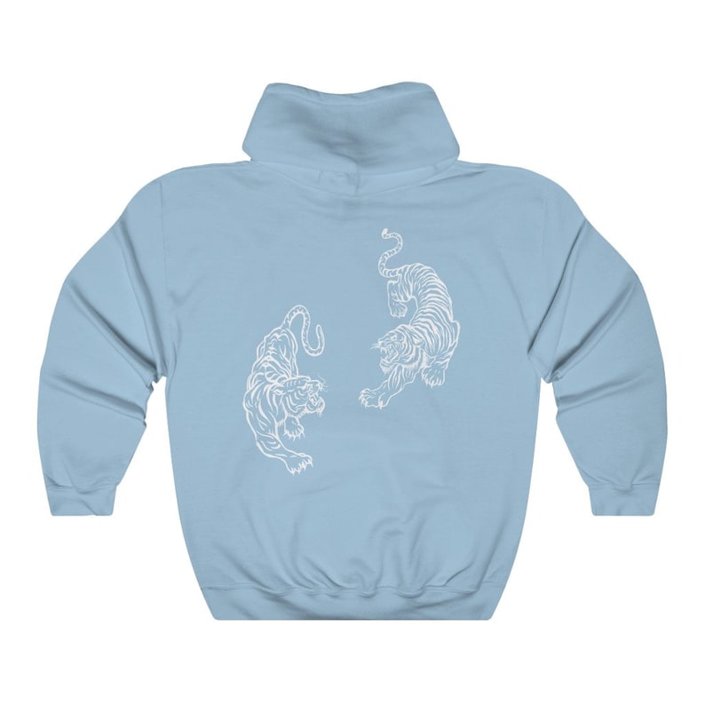 May include: A light blue hoodie featuring a white graphic of two tigers facing each other.