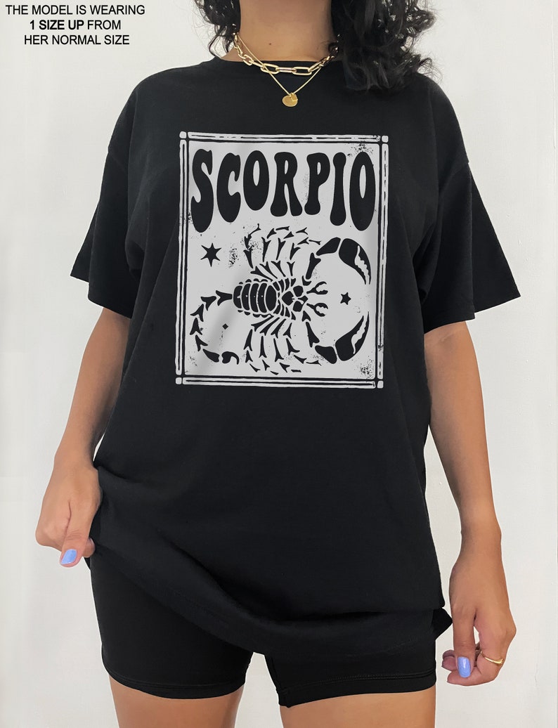 May include: Black oversized t-shirt with a white graphic of a scorpion and the word "SCORPIO" in a vintage style font.