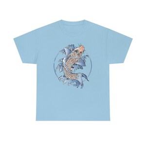 May include: A light blue t-shirt with a graphic of a blue and orange koi fish swimming in a circle of blue waves.