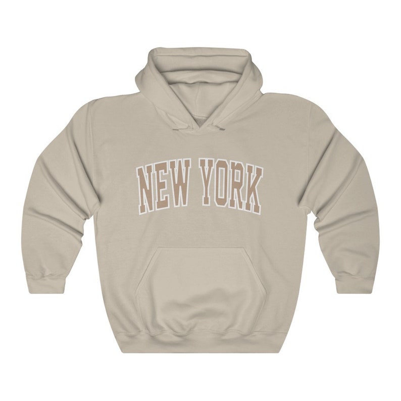 May include: A beige hooded sweatshirt with the text "NEW YORK" in brown letters with a white outline.