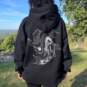 May include: Black hooded sweatshirt with a white graphic print of two koi fish swimming in a circle on the back.