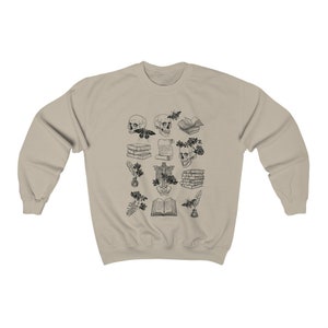 May include: A beige sweatshirt with a black and white print of various anatomical illustrations, including skulls, books, and flowers.