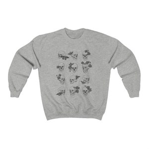K&ouml;nnte beinhalten: Grauer Pullover mit einem Muster aus schwarzen und wei&szlig;en Totenk&ouml;pfen mit Blumen und Schmetterlingen.