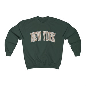 May include: A dark green sweatshirt with the text "NEW YORK" in a beige color.