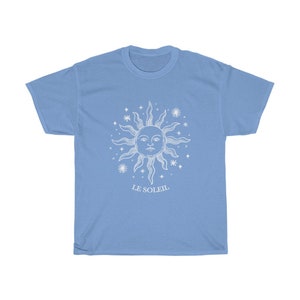 May include: A light blue t-shirt with a white graphic of a sun with a face and stars. The text "LE SOLEIL" is printed below the sun.