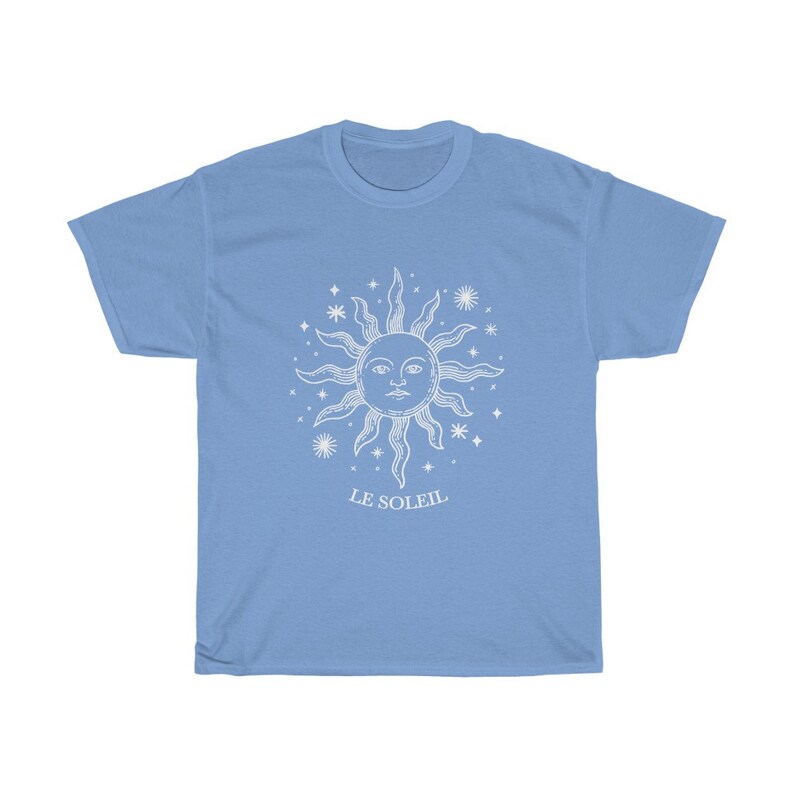 May include: A light blue t-shirt with a white graphic of a sun with a face and stars. The text "LE SOLEIL" is printed below the sun.