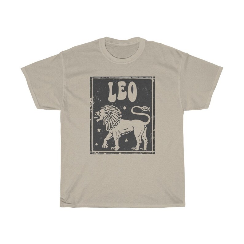 K&ouml;nnte beinhalten: Ein beiges T-Shirt mit einer Grafik im Vintage-Stil eines L&ouml;wen und dem Wort "LEO" in einer Retro-Schrift.