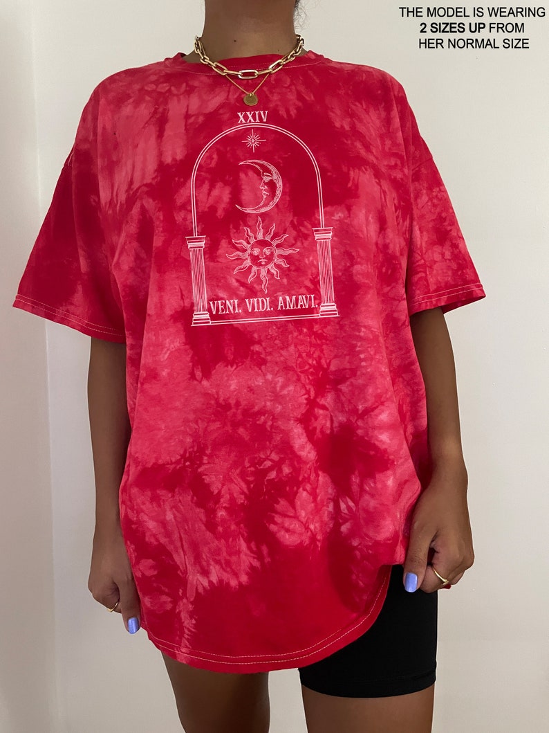 May include: Red tie-dye t-shirt with a white graphic of a sun, moon, and archway with the text "XXIV" and "VENI. VIDI. AMAVI."