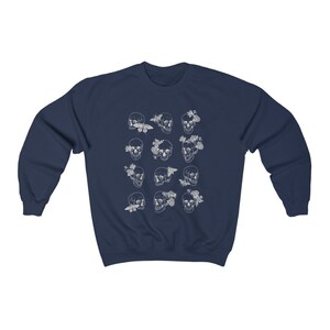 K&ouml;nnte beinhalten: Marineblauer Sweatshirt mit einem wei&szlig;en Druck von mehreren Sch&auml;deln mit floralen und Schmetterlingsakzenten.