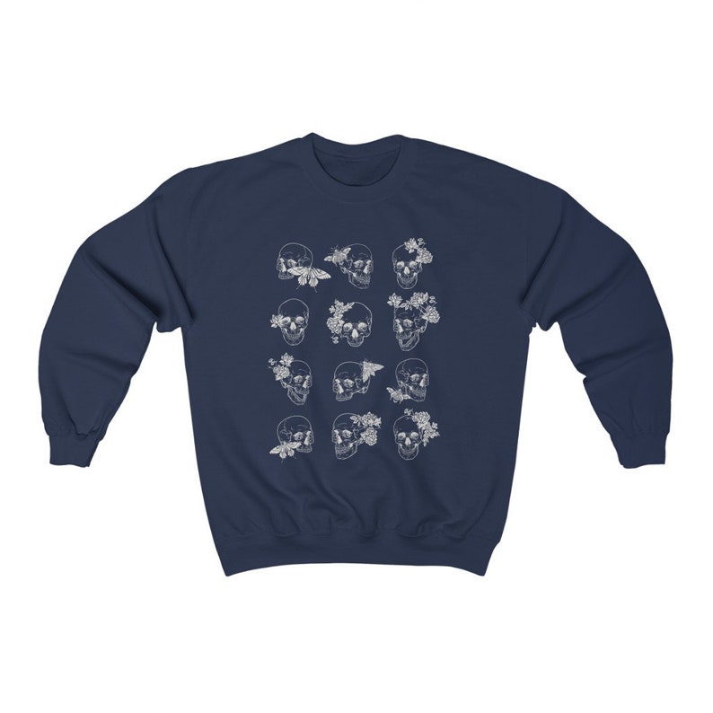 K&ouml;nnte beinhalten: Marineblauer Sweatshirt mit einem wei&szlig;en Druck von mehreren Sch&auml;deln mit floralen und Schmetterlingsakzenten.