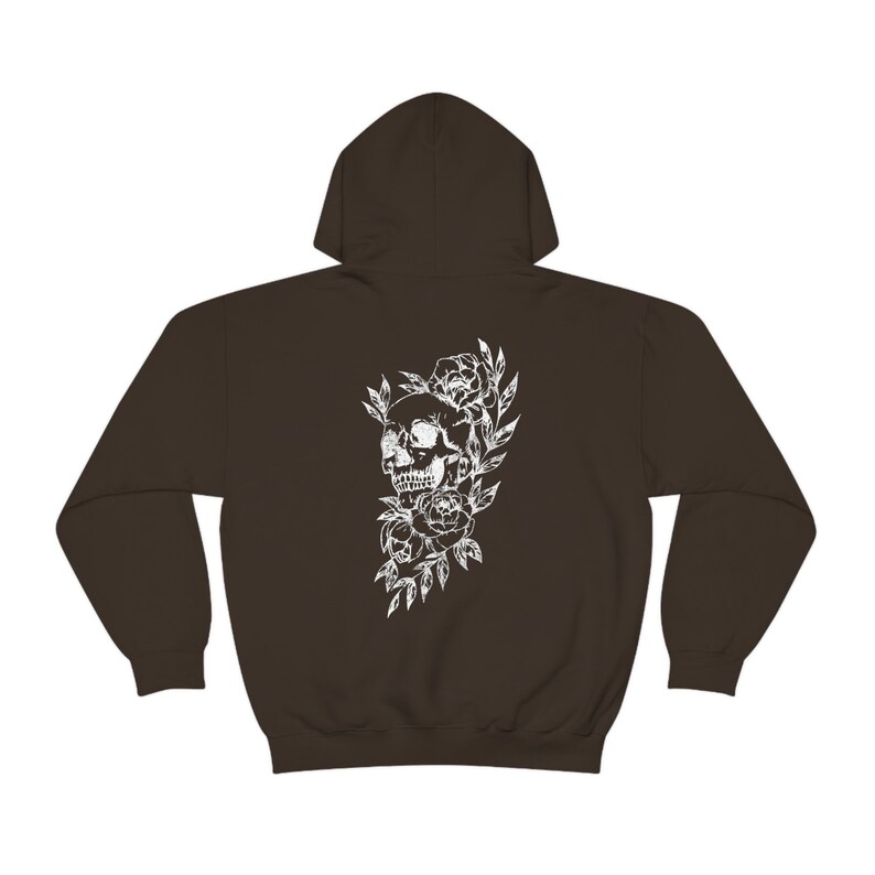 Puede incluir: Una sudadera con capucha marr&oacute;n oscuro con un estampado blanco de una calavera rodeada de flores.
