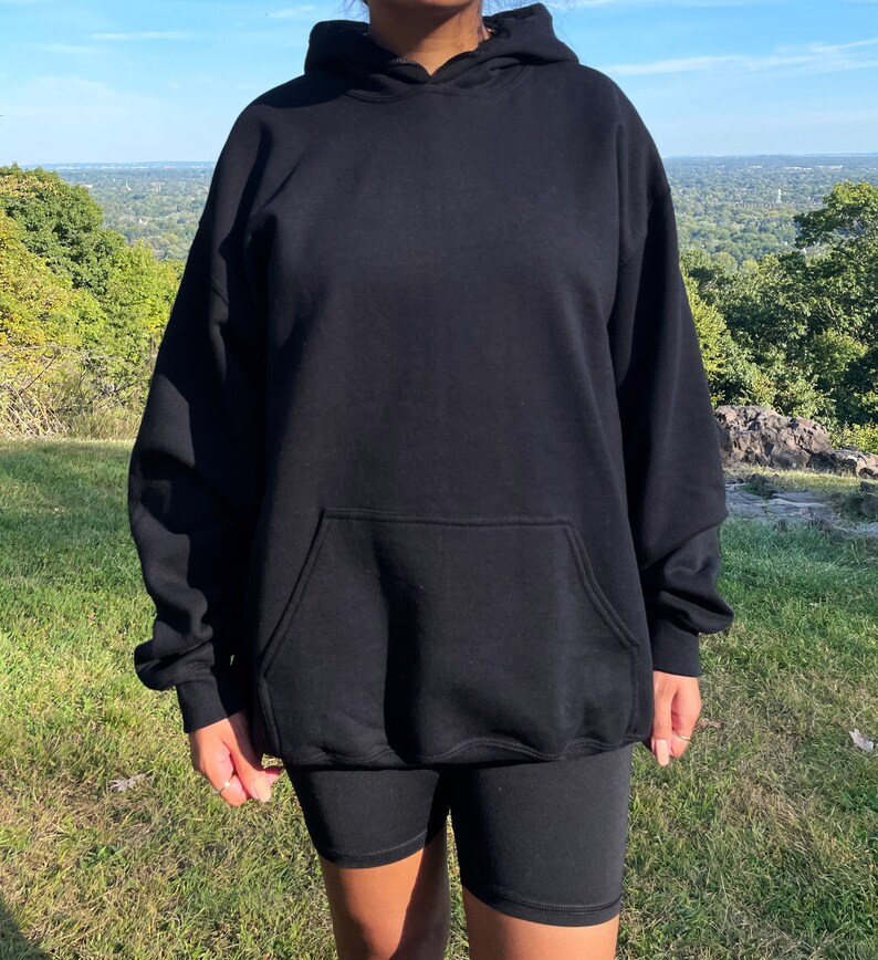 May include: A black oversized hoodie with a kangaroo pocket. The hoodie is made of a soft, comfortable fabric and has a relaxed fit.