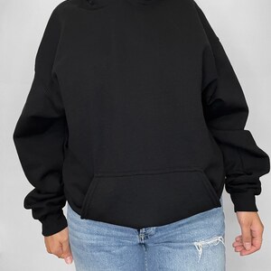 May include: Black oversized hoodie with a kangaroo pocket. The model is wearing a size up from their normal size.