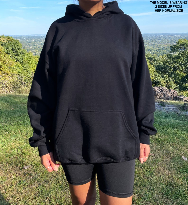 May include: Black oversized hoodie with a kangaroo pocket. The model is wearing the hoodie two sizes up from her normal size.