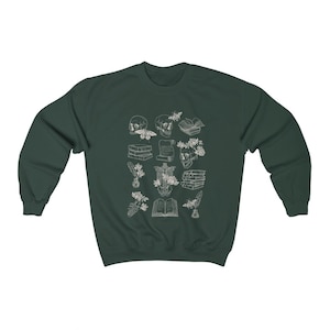 May include: A dark green sweatshirt with a white design of various anatomical illustrations, including a skull, a skeleton, flowers, and books. The design is reminiscent of vintage medical illustrations.
