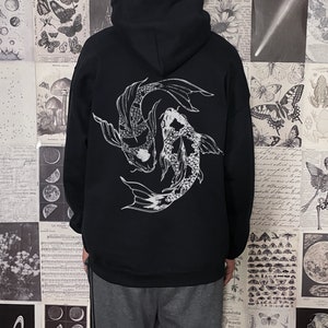 May include: Black hoodie with a white graphic of two koi fish swimming in a circle. The model is wearing a size up from their normal size.