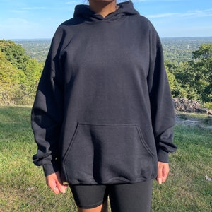 May include: A black hooded sweatshirt with a kangaroo pocket. The sweatshirt is made of a soft, comfortable fabric and has a relaxed fit.