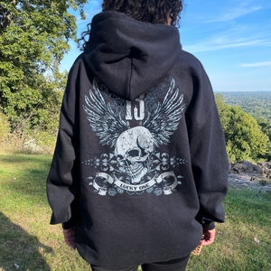 May include: Black hooded sweatshirt with a skull and wings graphic on the back. The graphic includes the text "Lucky One".