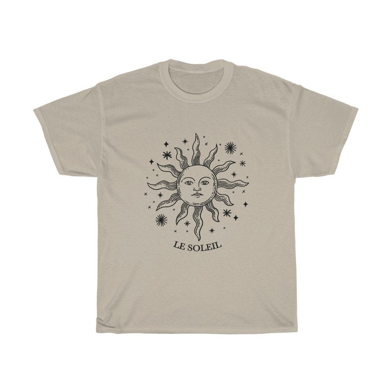May include: A beige t-shirt with a black graphic of a sun with a face and stars around it. The text "LE SOLEIL" is below the graphic.