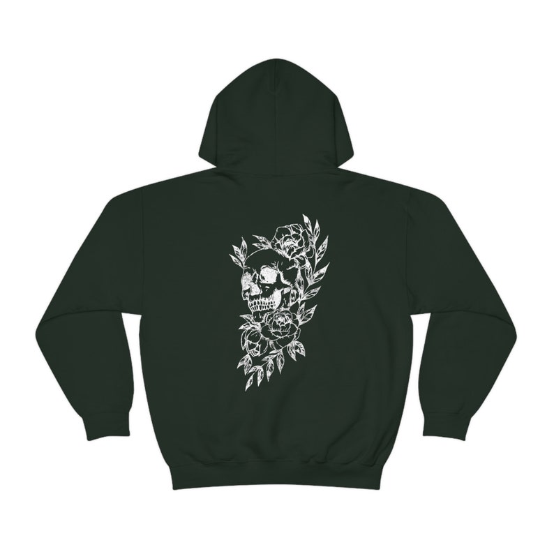 Puede incluir: Una sudadera con capucha verde oscuro con un estampado blanco de una calavera rodeada de flores.