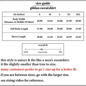 May include: Size chart for a Gildan sweatshirt, showing measurements in inches for body width, full body length, and sleeve length for sizes S, M, L, XL, and 2XL. The chart also includes a scale showing overall fit from small to big, with a dot indicating true to size. The text below the chart states that the style is unisex and fits like a men's sweatshirt, but it fits slightly smaller than true to size. It also recommends going up one size for a better fit and to go with the larger size if between sizes. The text also suggests viewing a sizing video for reference.