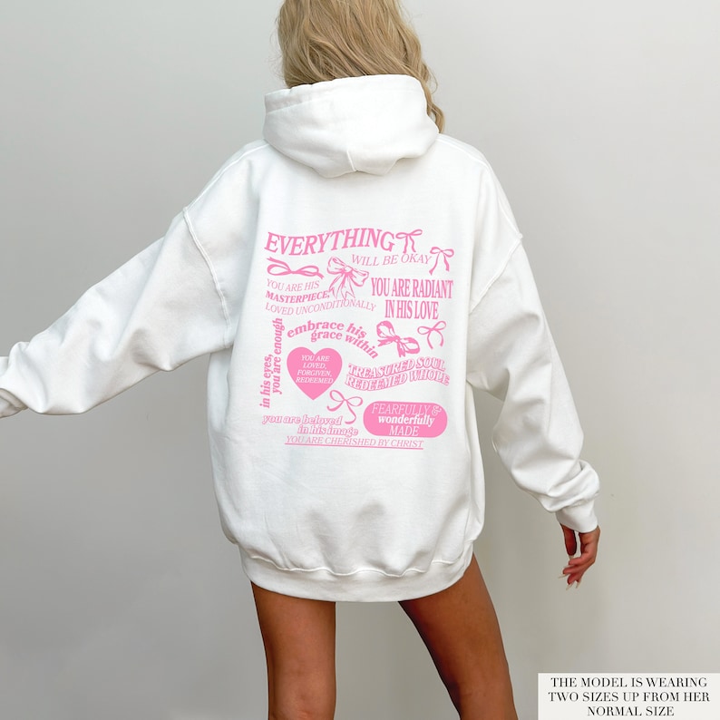May include: White hoodie with a pink graphic print that says "Everything will be okay" and other inspirational messages. The model is wearing the hoodie two sizes up from her normal size.